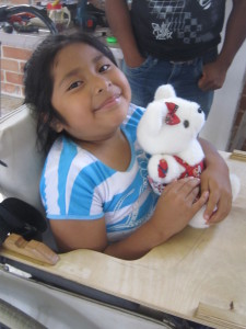 Child sitting in Wheelchair holding a teddy bear.